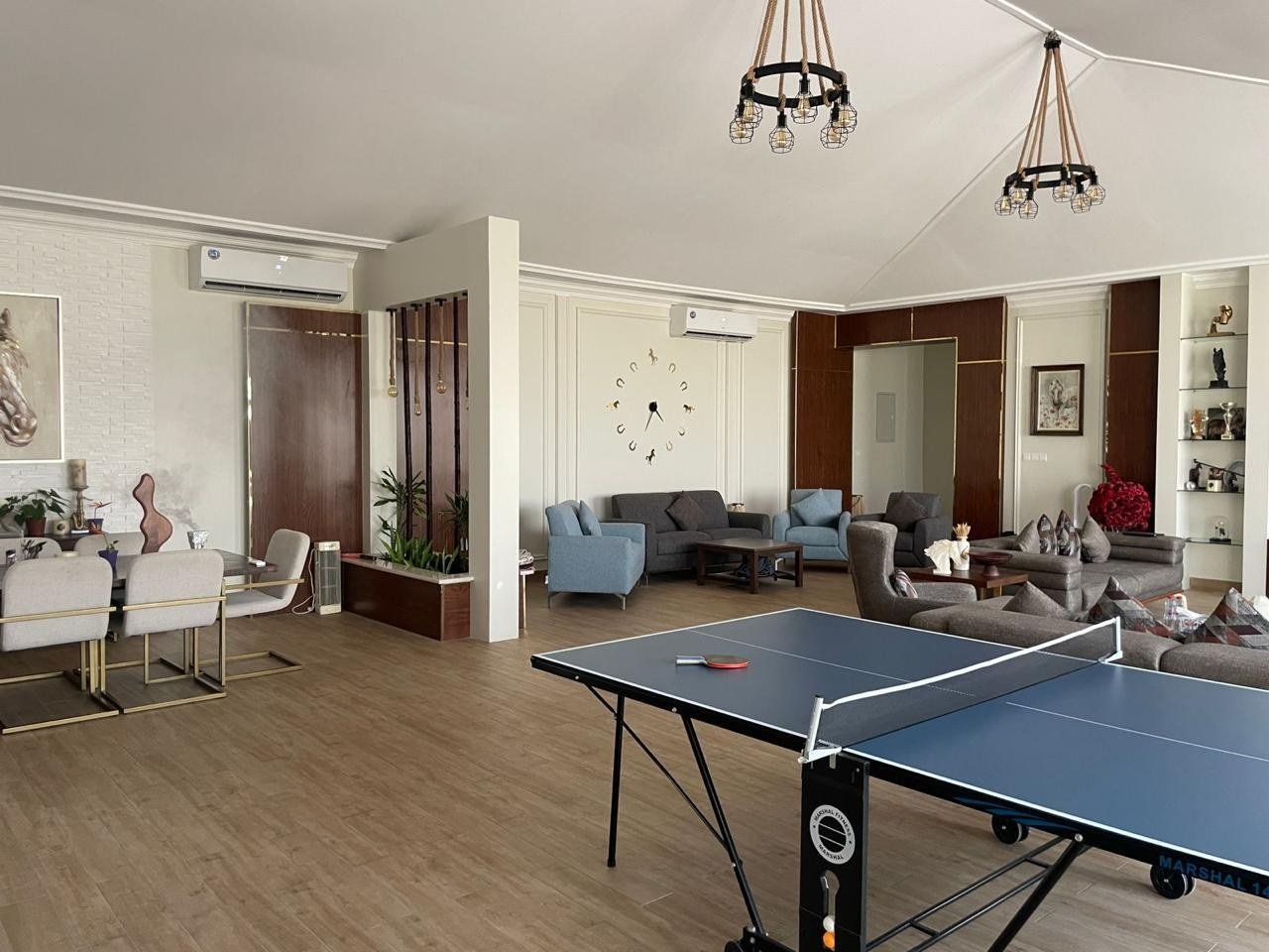 Games hall with a full-size table tennis table under lantern chandeliers.