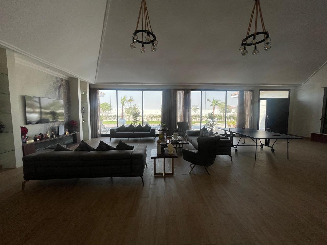 Lounge with dark leather seating facing full-height glazing onto the estate grounds.