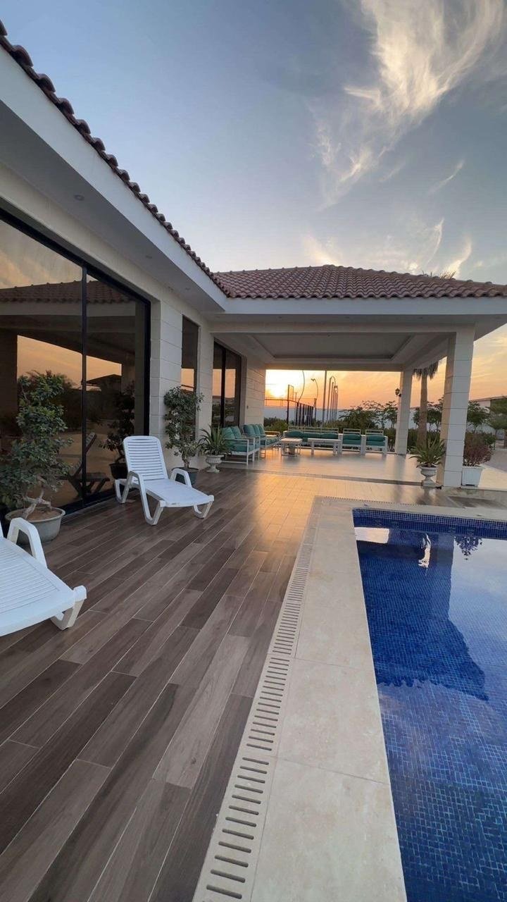 Pool and covered terrace under a pink dusk sky.