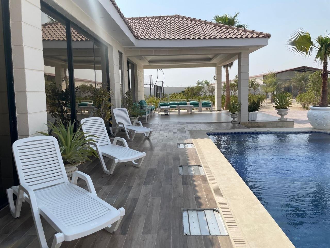 White loungers on a timber deck running alongside the pool.