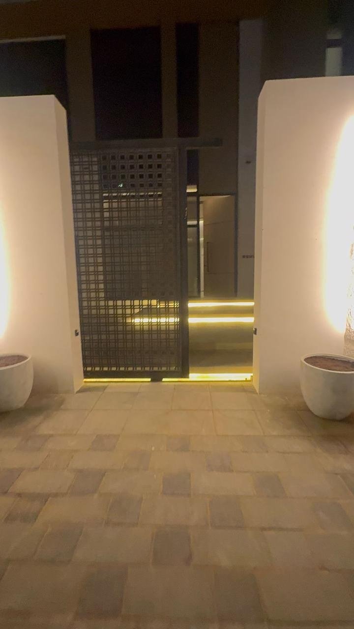 Backlit stone screen glowing between two sculptural pedestal basins.